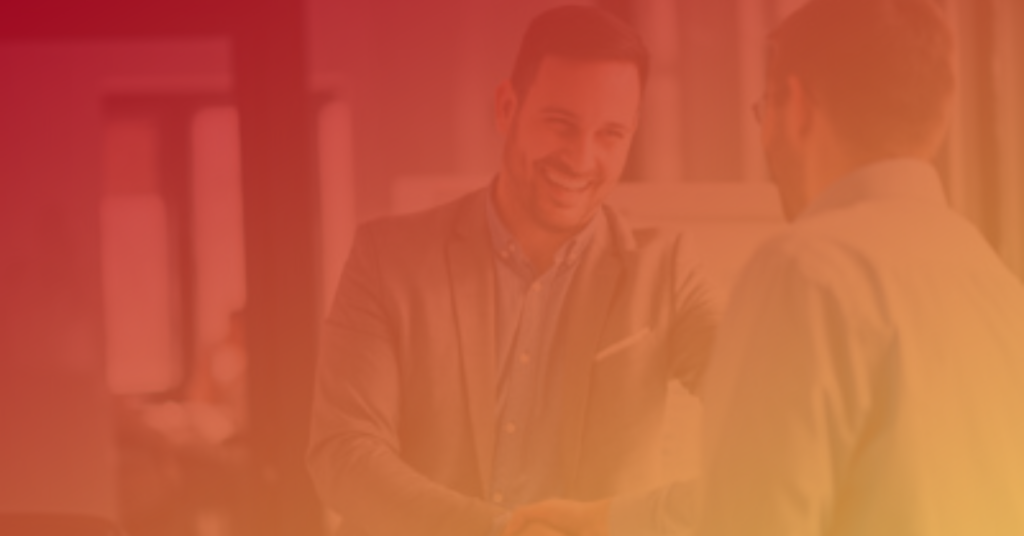 Two men shaking hands, smiling, in a warmly lit office
